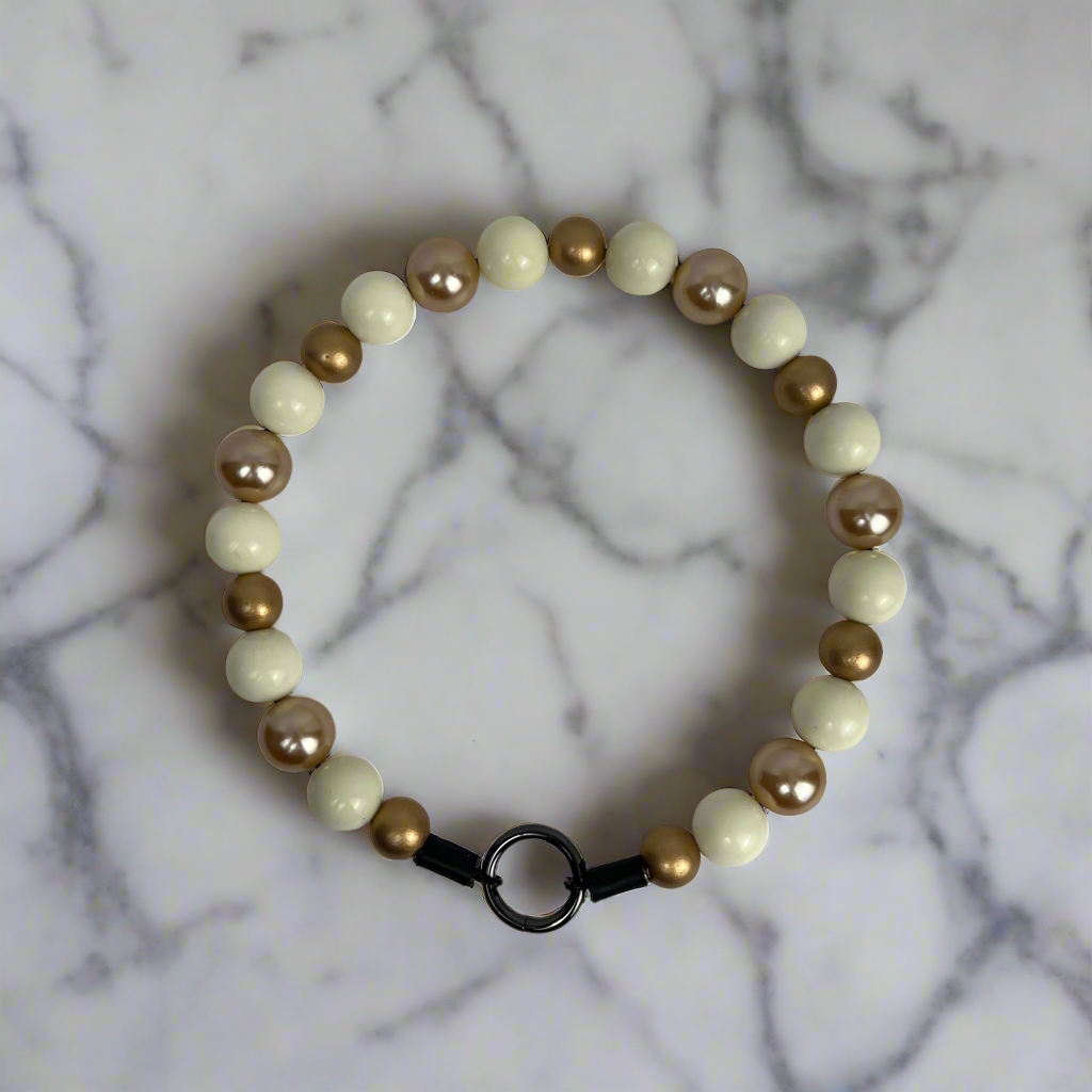 Beaded bracelet with gold and white beads on a marble background