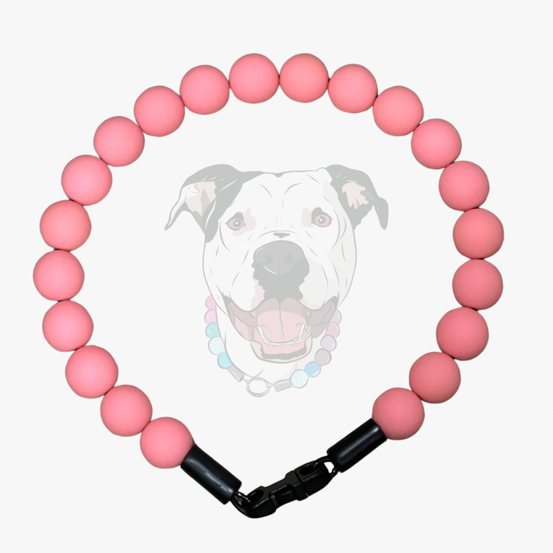 A pink acrylic beaded dog collar with a black quick-release clasp, displayed against a light gray background with a faint graphic of a dog's face.