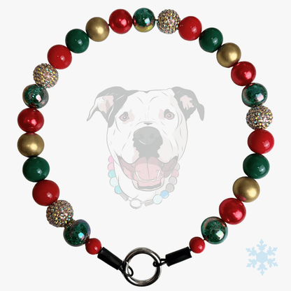 A Christmas-themed beaded dog collar featuring red, green, and metallic gold beads, with some glittery silver beads and a black metal clasp. A faint graphic of a dog wearing the collar is visible in the background.