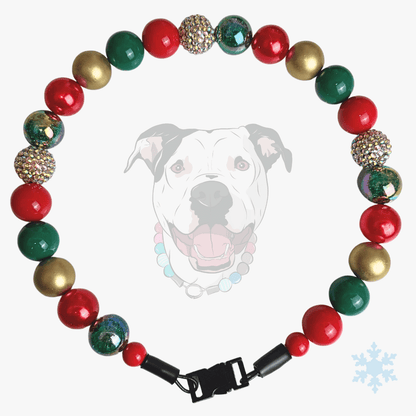 A Christmas-themed beaded dog collar with red, green, and gold beads, including some glittery and marbled accents, displayed on a light gray background with a faint dog graphic and a small snowflake icon.