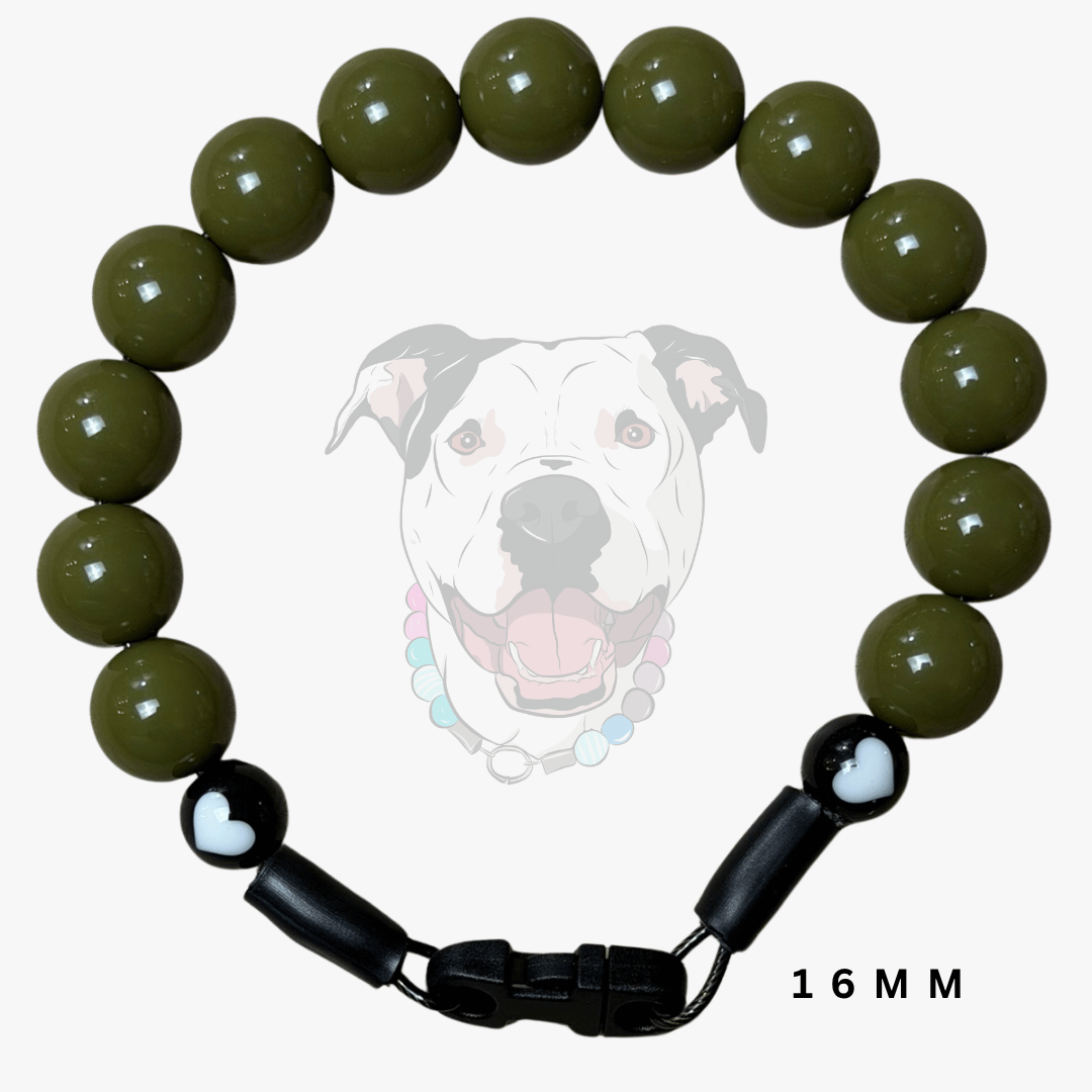 A beaded dog collar or bracelet made of glossy olive green round beads, with black adjustable slider clasp ends and a small white heart detail on one end. A faint dog face graphic appears behind the product, and '16 MM' text is shown at the bottom right.