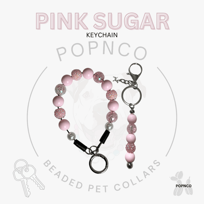 Pink sugar beaded pet keychain with silver metal rings, a lobster clasp, and a black snap connector, displayed on a light gray background with 'PINK SUGAR KEYCHAIN' and 'POPNCO' branding.