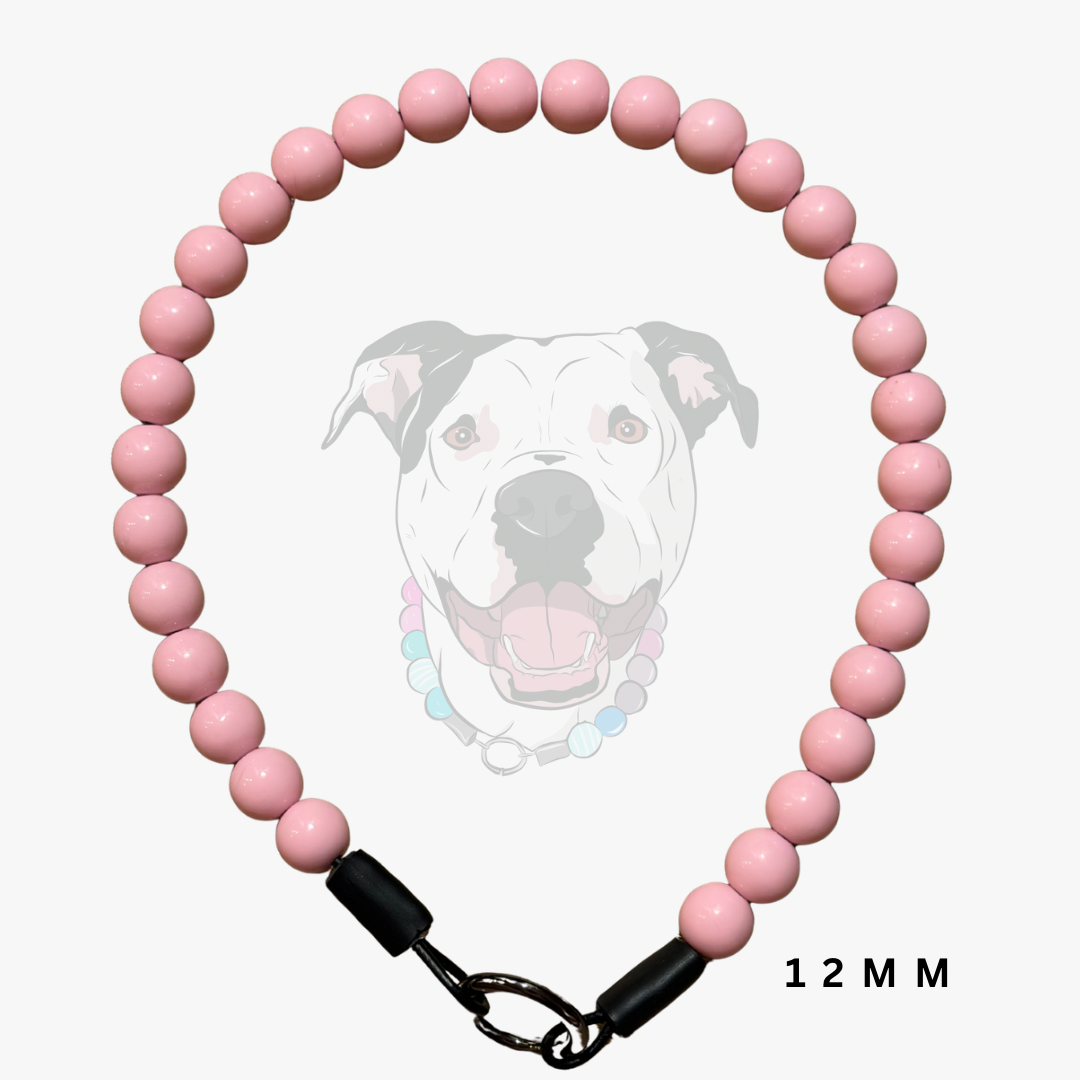 A pink beaded dog collar made of glossy round beads, featuring black plastic end caps and a silver metal clasp. A faint graphic of a dog's face is visible in the background, and the text '12 MM' is printed in the bottom right corner.