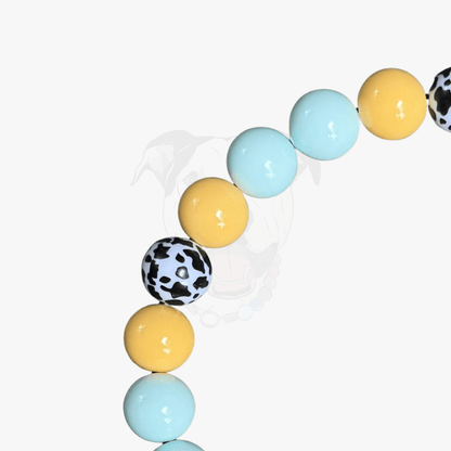 POPNCO Bonnie Beaded Pet Collar Blue and  Yellow Cow 20mm Square on White Background, featuring close up of yellow light blue and black and white cow print acrylic beads. 