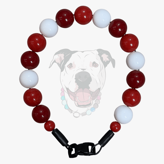 A beaded dog collar featuring alternating glossy red and white round beads, with a black plastic buckle closure at the bottom. A faint graphic of a white pitbull-type dog wearing the collar is overlaid in the center on a light gray background.