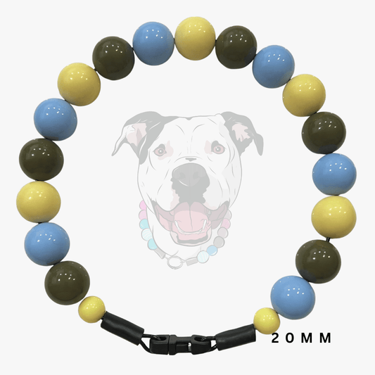 A beaded dog collar necklace with alternating light blue, yellow, and olive green round beads, a black clasp, and a faint dog face graphic in the background with '20MM' text.