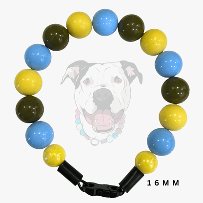 A beaded dog collar with glossy round beads in light blue, yellow, and dark olive green, featuring a black plastic clasp. A faint graphic of a dog wearing the collar is visible in the background, and '16 MM' is printed at the bottom right.