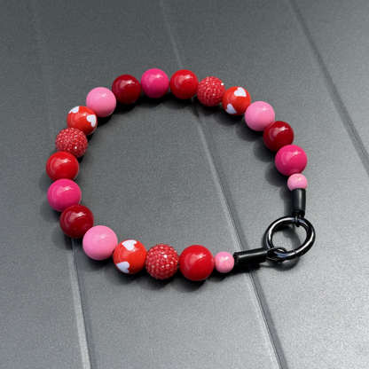 POPNCO Cupid Beaded Pet Collar. Valentines Holiday Collection pink and red acrylic and resin beads on aircraft grade stainless steel wire. Cupid Red and Pink beaded Pet Collar from POPNCO laying on a grey Table