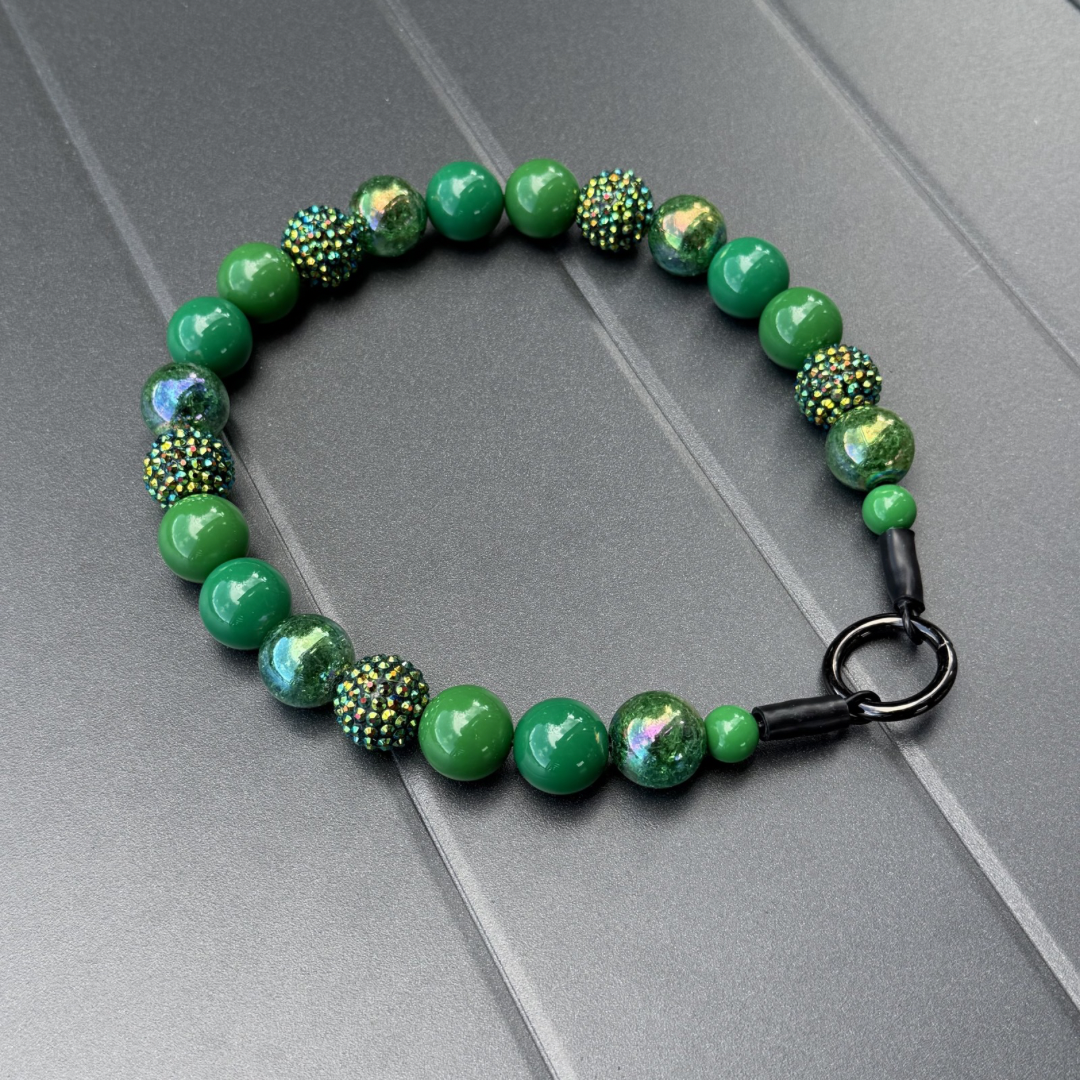 POPNCO Evergreen Beaded Pet Collar. Green Acrylic and Resin Beads on Aircraft Grade Stainless Steel Wire. Green beaded pet collar from POPNCO laying on a gray surface