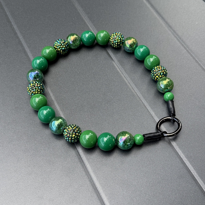 POPNCO Evergreen Beaded Pet Collar. Green Acrylic and Resin Beads on Aircraft Grade Stainless Steel Wire. Green beaded pet collar from POPNCO laying on a gray surface