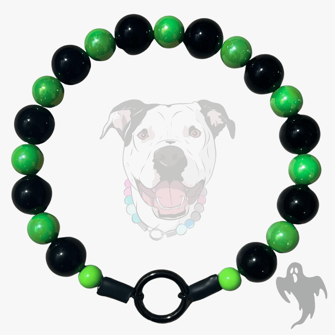A beaded dog collar featuring alternating glossy black and vibrant green beads, finished with a black metal ring clasp. The product is displayed against a light gray background with a faint graphic of a pitbull dog wearing the collar and a small ghost shadow in the corner.