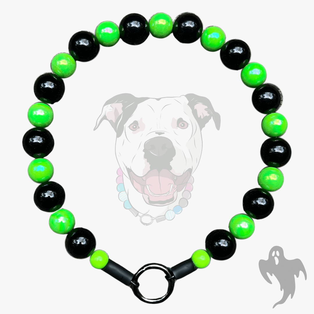 A beaded dog collar featuring alternating glossy black and bright neon green beads, finished with a black metal ring clasp, shown against a light gray background with a faint dog graphic.