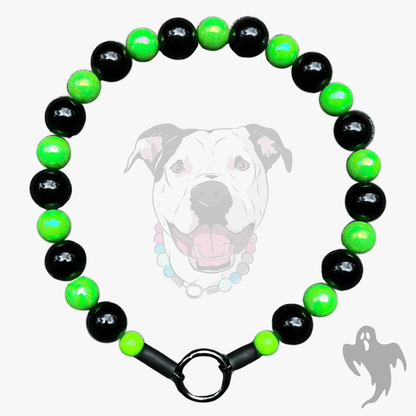A beaded dog collar featuring alternating glossy black and bright neon green beads, finished with a black metal ring clasp, shown against a light gray background with a faint dog graphic.