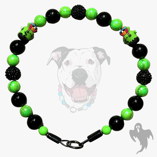 A beaded dog collar featuring alternating black and bright lime green beads, accented with two green monster beads and a black clasp, displayed against a light gray background with a faint dog graphic.
