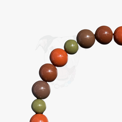 A close-up of a beaded strand with glossy round beads in rust orange, medium brown, and olive green, arranged in a curved line against a plain white background.