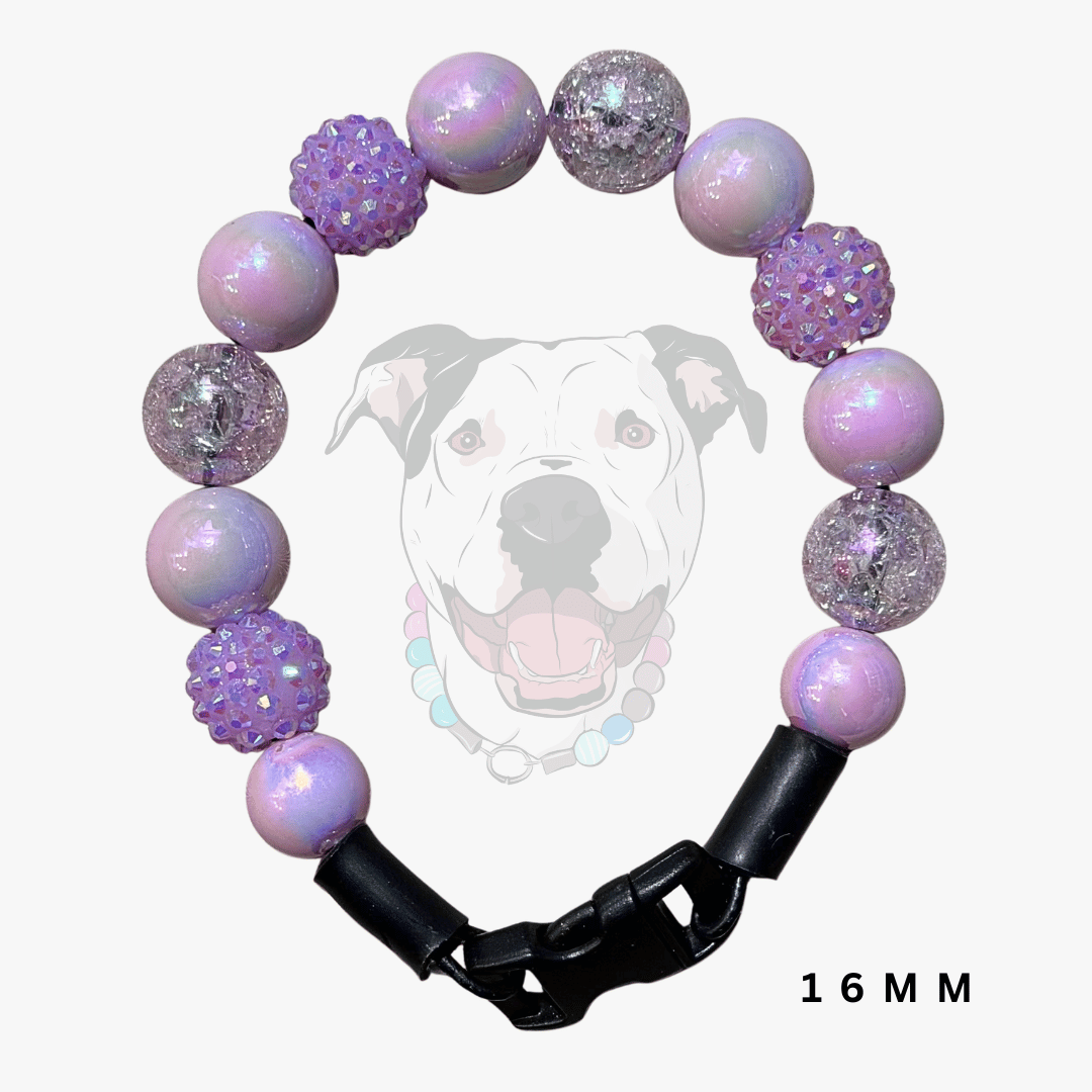 A beaded dog collar with lavender and purple beads, including textured rhinestone and glitter beads, a black plastic buckle, and a faint dog graphic in the background with '16 MM' text at the bottom right.