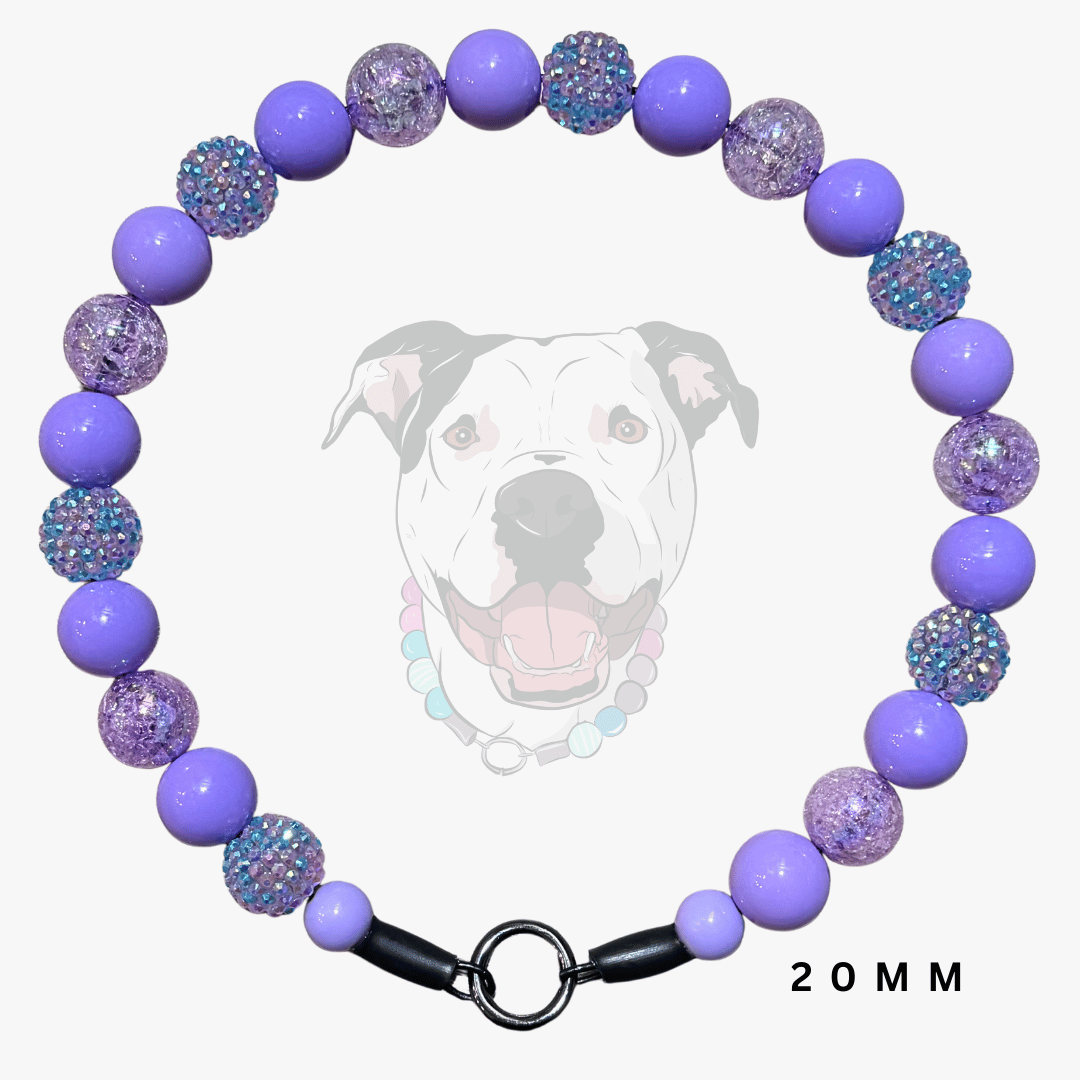 A beaded dog collar necklace with alternating smooth lavender-purple beads and textured purple beads covered in iridescent blue glitter. The collar has a black metal ring clasp and is displayed against a light gray background with a faint graphic of a dog's face and the text '20 MM'.