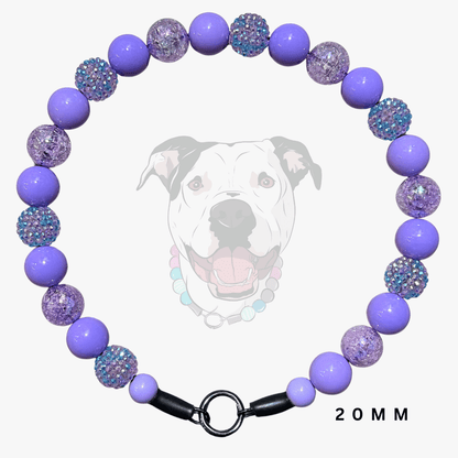 A beaded dog collar necklace with alternating smooth lavender-purple beads and textured purple beads covered in iridescent blue glitter. The collar has a black metal ring clasp and is displayed against a light gray background with a faint graphic of a dog's face and the text '20 MM'.