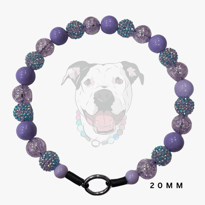A beaded dog collar necklace featuring purple and lavender beads, some smooth and some textured with iridescent glitter, displayed on a light gray background with a faint dog graphic and '20 MM' text.