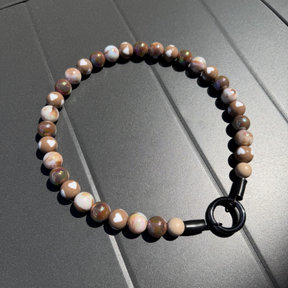 POPNCO Indulgence 16mm Beaded pet Collar.  The Beaded Collar is crafted on aircraft grade stainless steel wire and the waterproof beads are AB Shiny iridescent shades of brown in a alternating pattern mixed with double sided brown and cream hearts. Collar is laying flat on a black grey surface.
