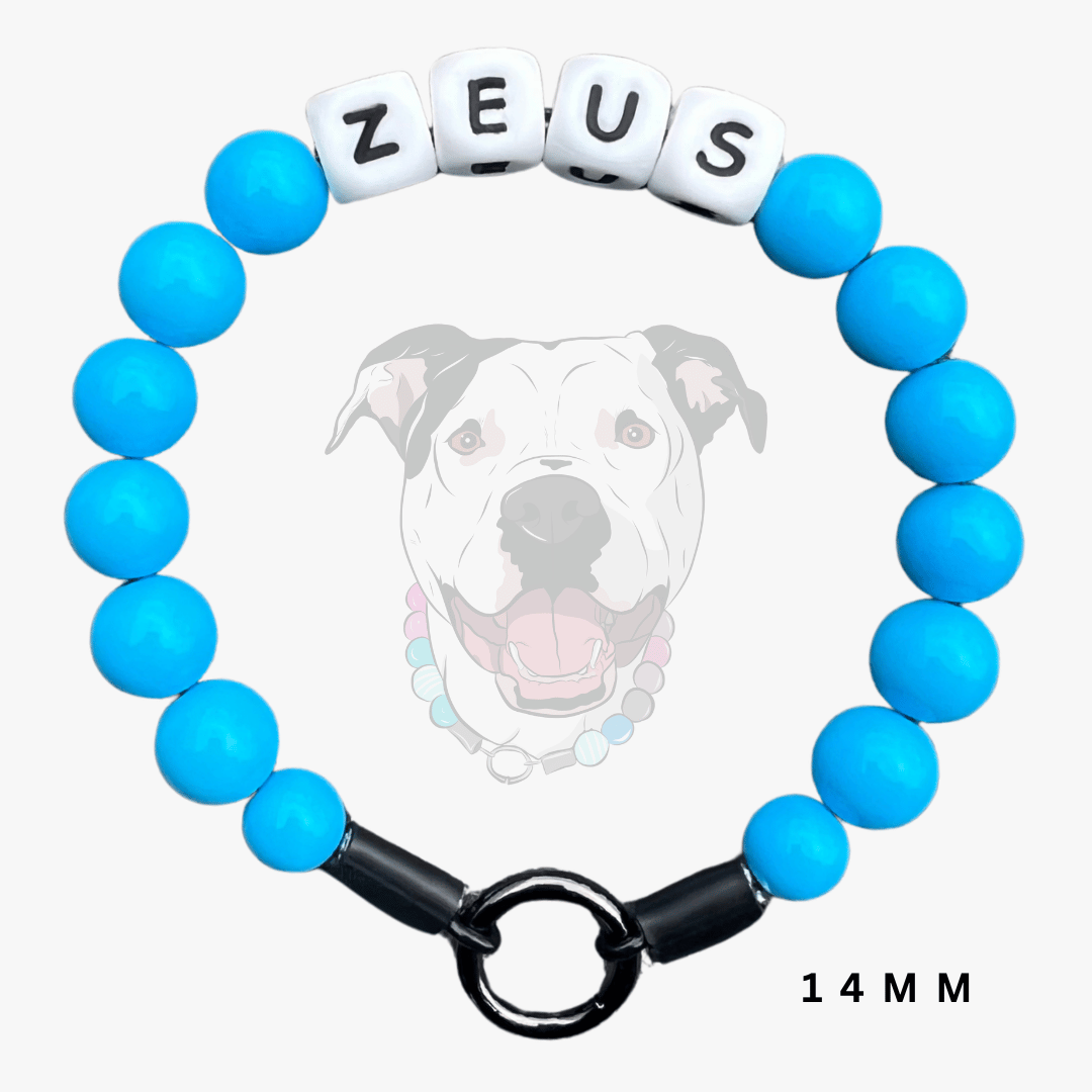 A beaded dog collar charm bracelet with bright blue round beads, a black toggle clasp, and white cube beads spelling 'ZEUS'. A faint dog illustration and the text '14 MM' appear on a light gray background.