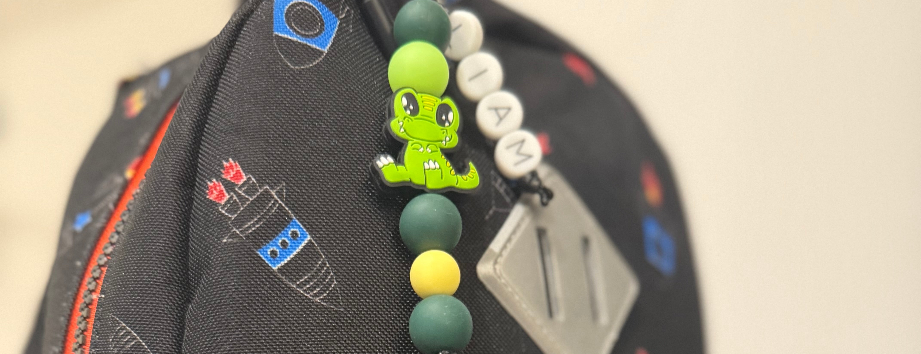 Close-up of a colorful backpack with a green alligator silicone beaded keychain charm from POPNCO. 