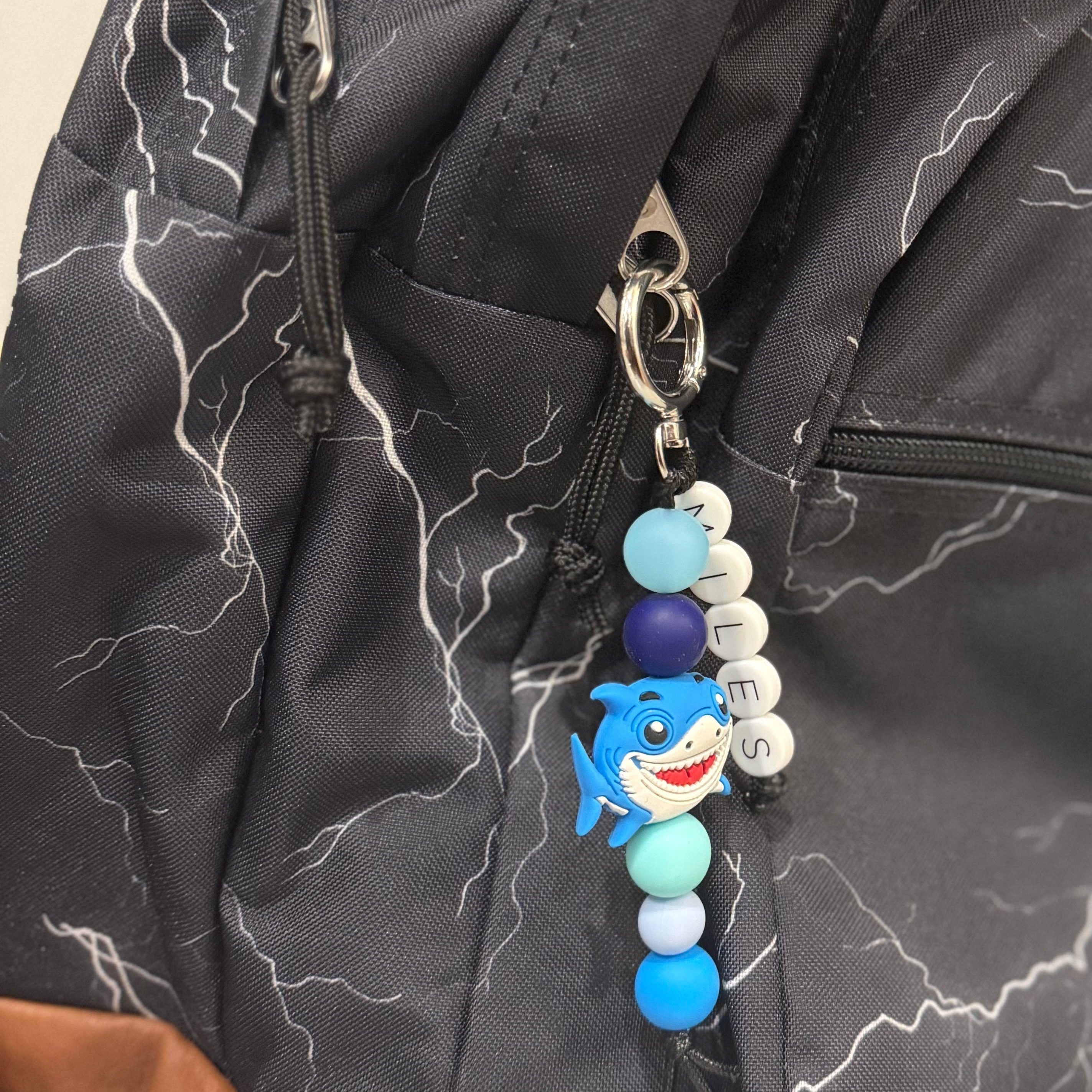 Keychain with blue beads and Silicone Shark on a black backpack from POPNCO. 