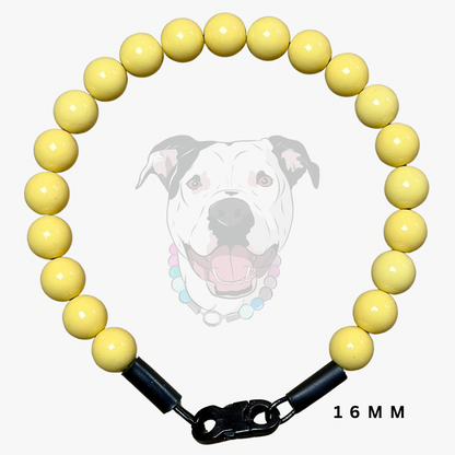 A yellow beaded dog collar with a black clasp and a 16mm width measurement label, shown against a light gray background with a faint dog graphic.
