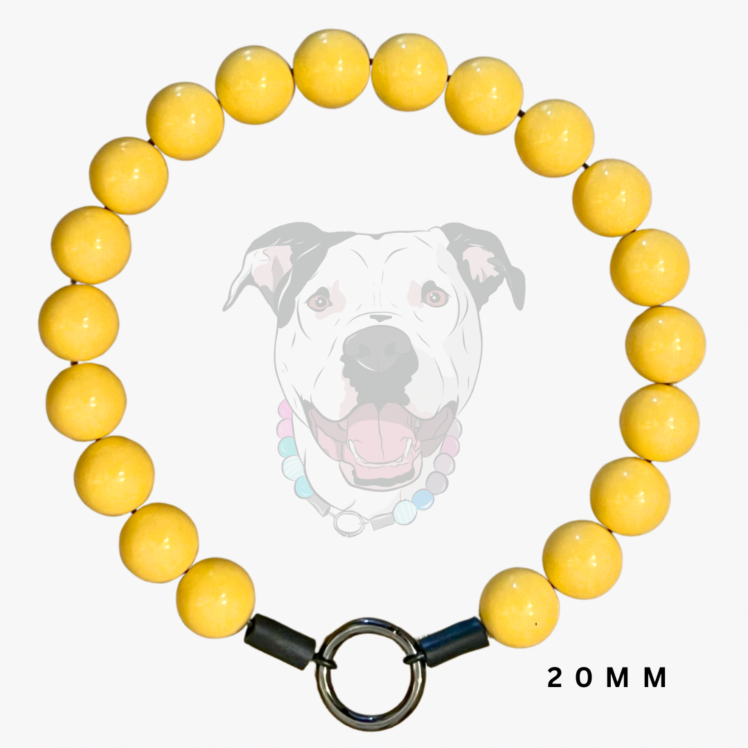 A yellow beaded dog collar with a silver metal ring clasp and black end caps, displayed against a light gray background with a faint dog illustration and '20 MM' text.