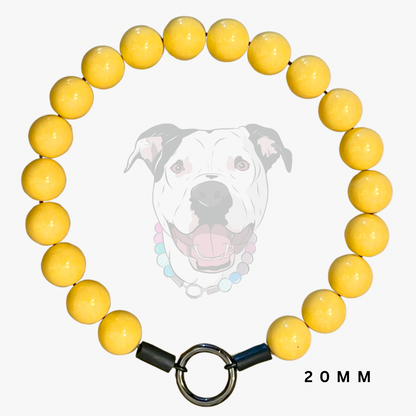 A yellow beaded dog collar with a silver metal ring clasp and black end caps, displayed against a light gray background with a faint dog illustration and '20 MM' text.