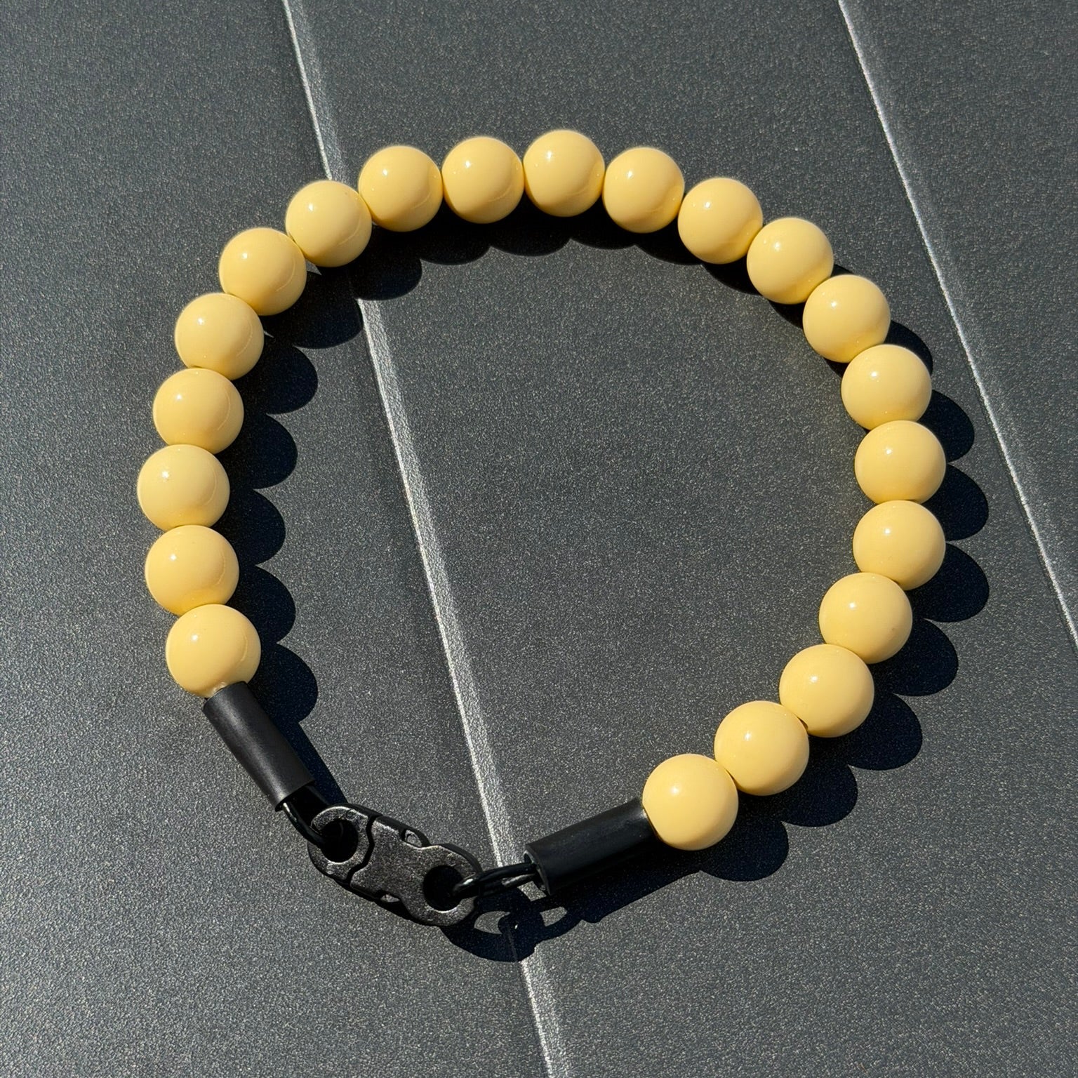 POPNCO Myrtle Beaded Pet collar 16mm. Solid Yellow Acrylic beads on aircraft grade stainless steel wire. Yellow beaded collar with a black metal clasp on a gray surface