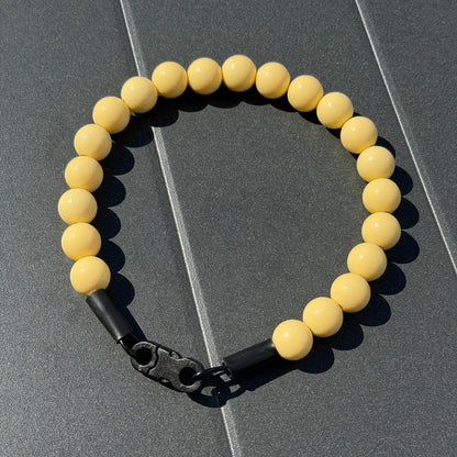 POPNCO Myrtle Beaded Pet collar 16mm. Solid Yellow Acrylic beads on aircraft grade stainless steel wire. Yellow beaded collar with a black metal clasp on a gray surface