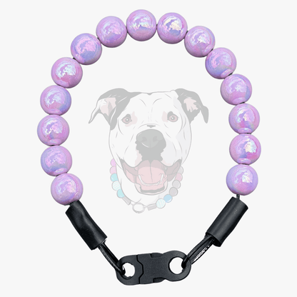 A beaded dog collar with iridescent lavender and purple beads, black leather loops, and a black plastic quick-release clasp, shown against a light gray background with a faint graphic of a dog's face.