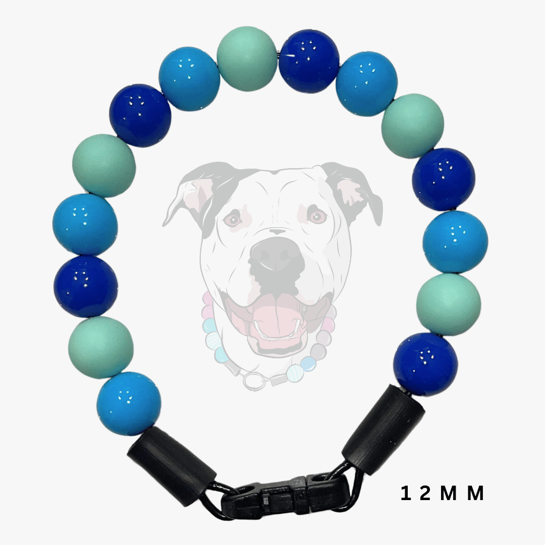 A beaded collar featuring alternating glossy blue and mint green round beads, finished with black plastic end caps and a black metal clasp. A faint graphic of a dog wearing the collar is displayed in the background, with '12 MM' text in the bottom right corner.