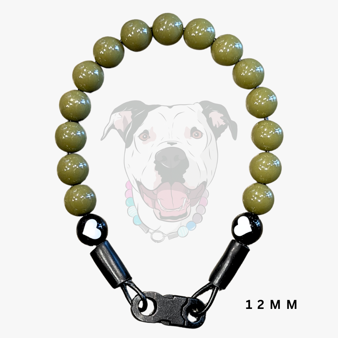 A dog collar made of olive green glossy round beads and black hardware, featuring a heart-shaped clasp and a black swivel clasp, shown against a light gray background with a faint dog graphic and '12 MM' text.