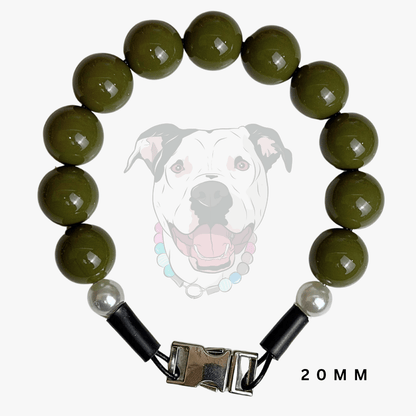 A beaded dog collar featuring glossy olive green round beads, a white pearl accent, black end caps, and a silver metal buckle. A faint graphic of a dog wearing the collar is displayed in the background, with '20MM' text in the bottom right corner.