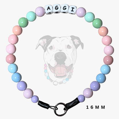 A pastel beaded dog collar with letter beads spelling 'AGGI' and a black clasp, shown on a light gray background with a faint dog illustration and '16MM' text.