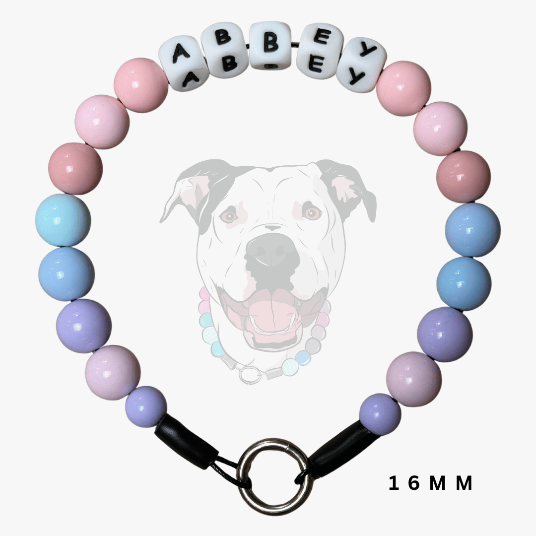 A pastel beaded dog collar with alternating pink, light blue, and lavender beads, featuring white letter beads spelling 'ABBEY' and a black clasp with a metal ring, shown against a light gray background with a faint dog graphic.