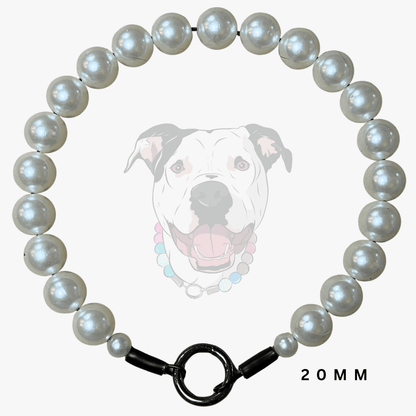 A 20mm pearl collar necklace arranged in a circle, featuring lustrous white pearls and a black toggle clasp, shown against a light gray background with a faint dog illustration and '20MM' text.