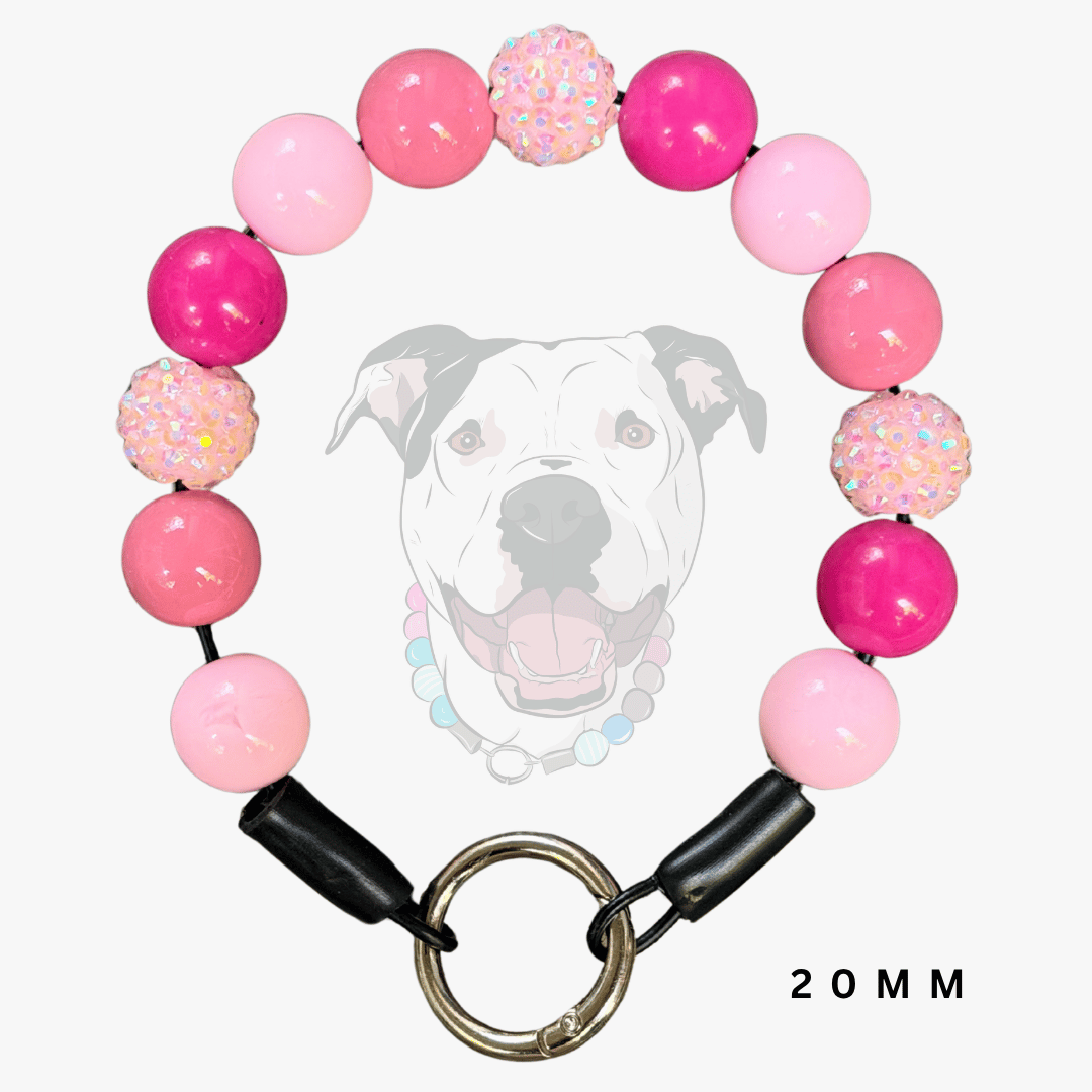 A pink beaded dog collar with a metal ring clasp, shown against a light gray background with a faint dog graphic and the text '20MM'.