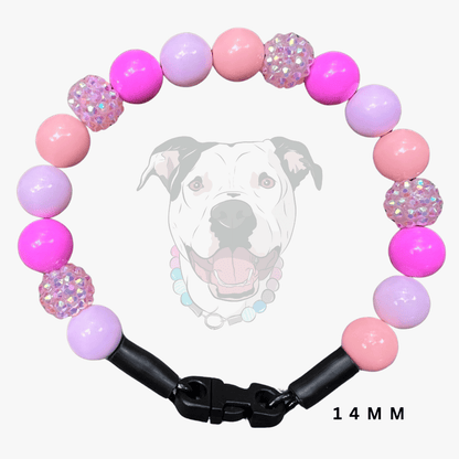 A dog collar made of pink and lavender beads, with two silver rhinestone-covered round beads and a black plastic clasp. A faint graphic of a dog's face is visible in the background, and the text '14 MM' is shown in the lower right corner.