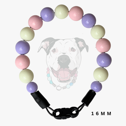 A beaded dog collar with pastel purple, pink, and pale yellow-green round beads, featuring a black plastic clasp and shown against a white background with a faint dog graphic and '16 MM' text.
