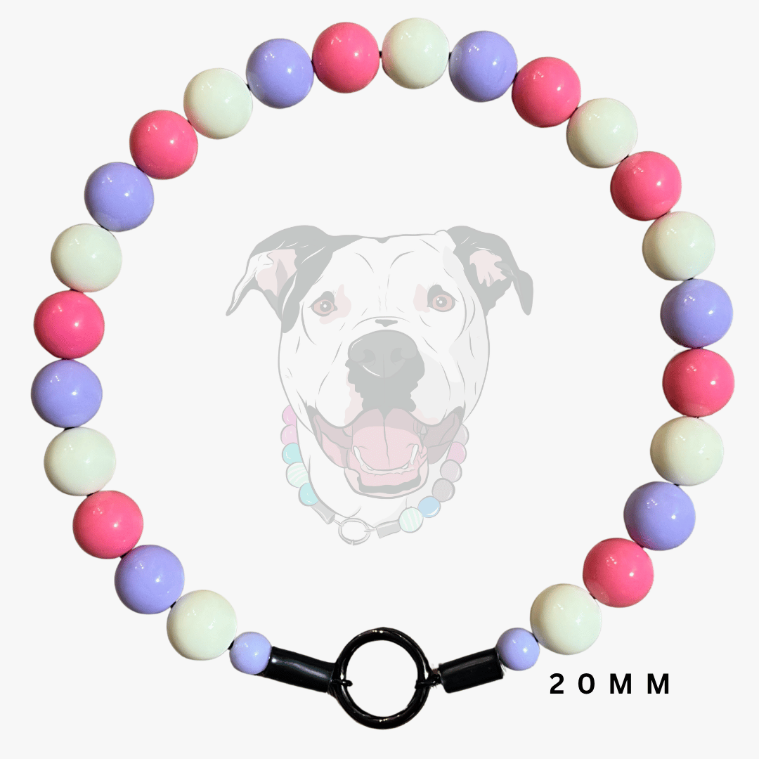 A beaded dog collar necklace made of glossy pastel beads in pink, lavender, cream, and light blue, arranged in a circle with a black toggle clasp. A faint dog face wearing the collar is visible in the background, and '20MM' is printed at the bottom right.