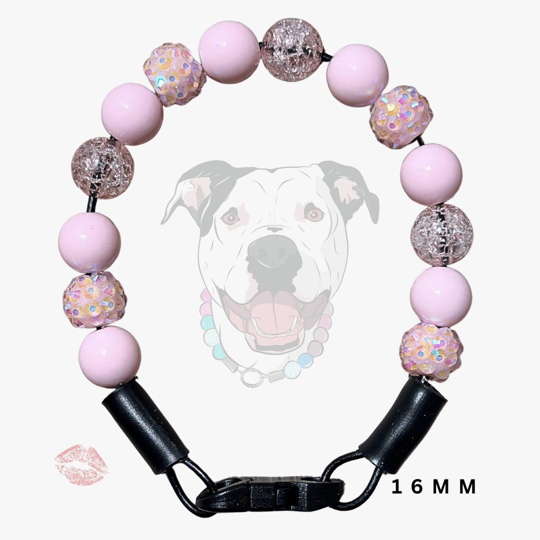 A pink beaded dog collar with black hardware and a black buckle clasp, shown on a light gray background with a faint dog graphic and '16MM' text.