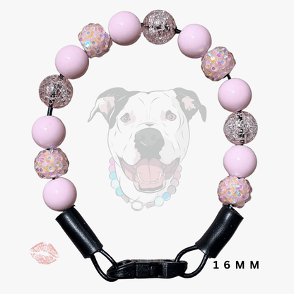 A pink beaded dog collar with black hardware and a black buckle clasp, shown on a light gray background with a faint dog graphic and '16MM' text.