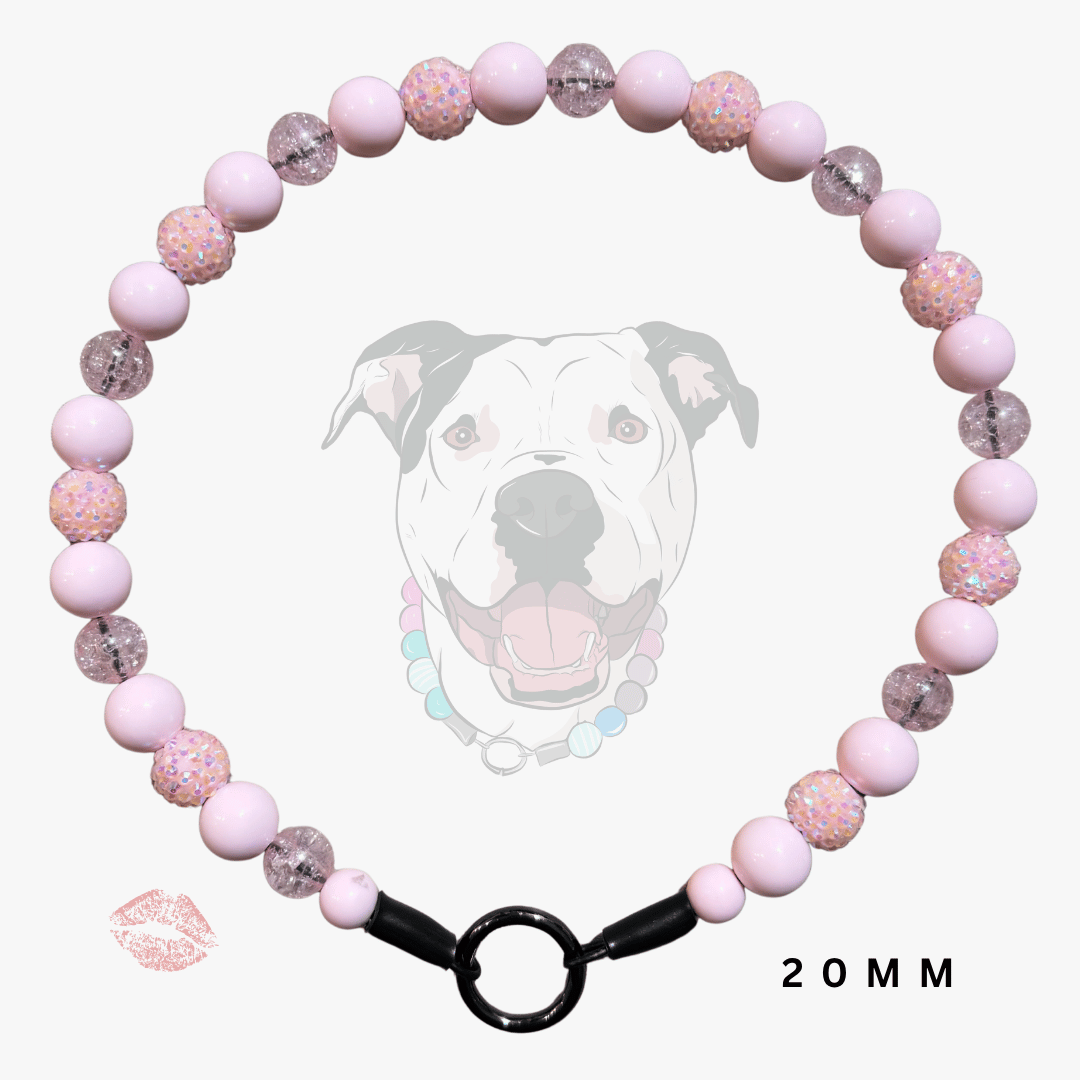 A pink beaded collar with alternating smooth light pink beads and glittery pink beads, featuring a black metal ring clasp. A faint dog graphic and a lip print are visible in the background, with '20MM' text at the bottom right.