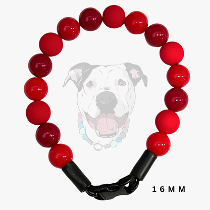 A red beaded dog collar with a black plastic clasp, shown against a light gray background with a faint graphic of a dog's face and the text '16 MM'.