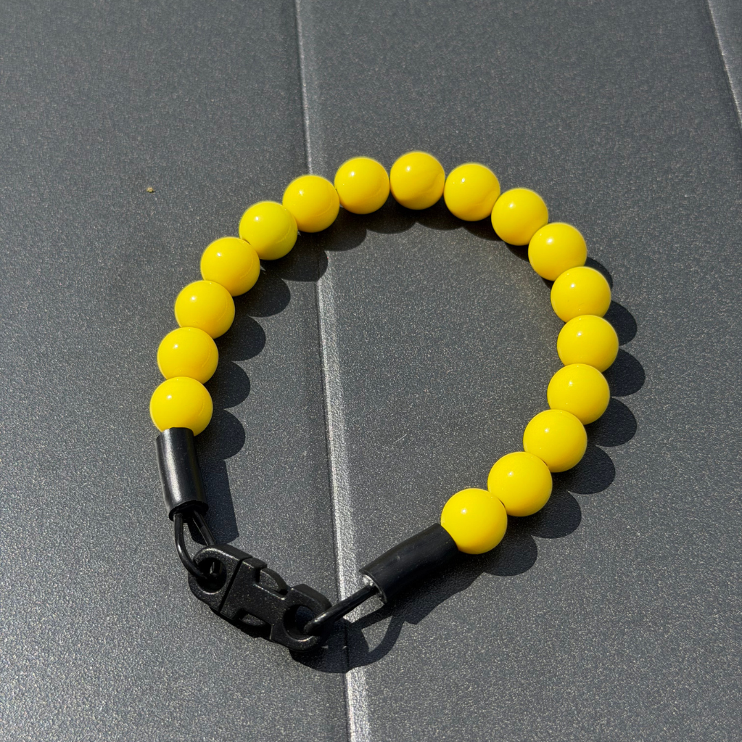 Popnco collar laying on a black table. It is a Classic Solid beaded pet Collar from POPNCO Called Sunny, featuring Solid warm 12mm Acrylic yellow beads.