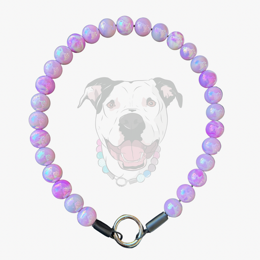 A beaded collar made of iridescent lavender and pink round beads with a silver metal ring clasp, shown against a light gray background with a faint dog graphic behind it.