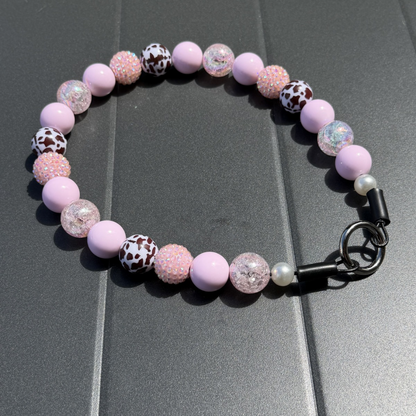 POPNCO handcrafted beaded pet collar Jolene laying flat on a black table featuring pale pink solid, crackle and rhinestone bayberries mixed with brown cow print beads. 
